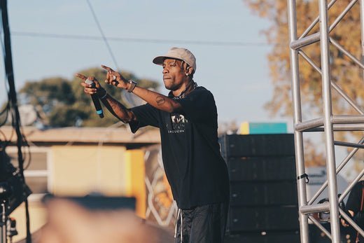 Travis scott holding a microphone pointing out to the crowd