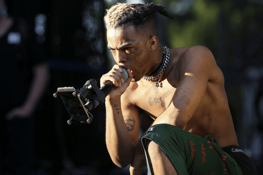 XXXTentacion performing holding microphone to his mouth while emotionally looking at the audience.